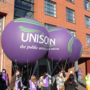 3 giant Unison parade balloons attached to people in the street