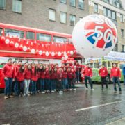 People in red hoodies with London bus and parade sphere