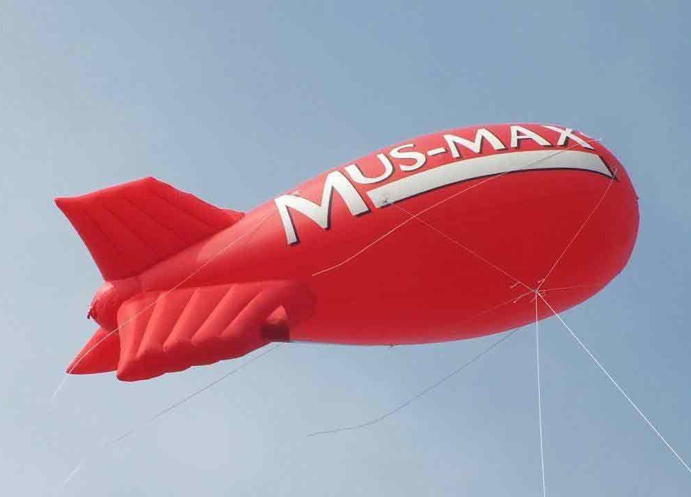 Mus-Max red blimp flying in a blue sky