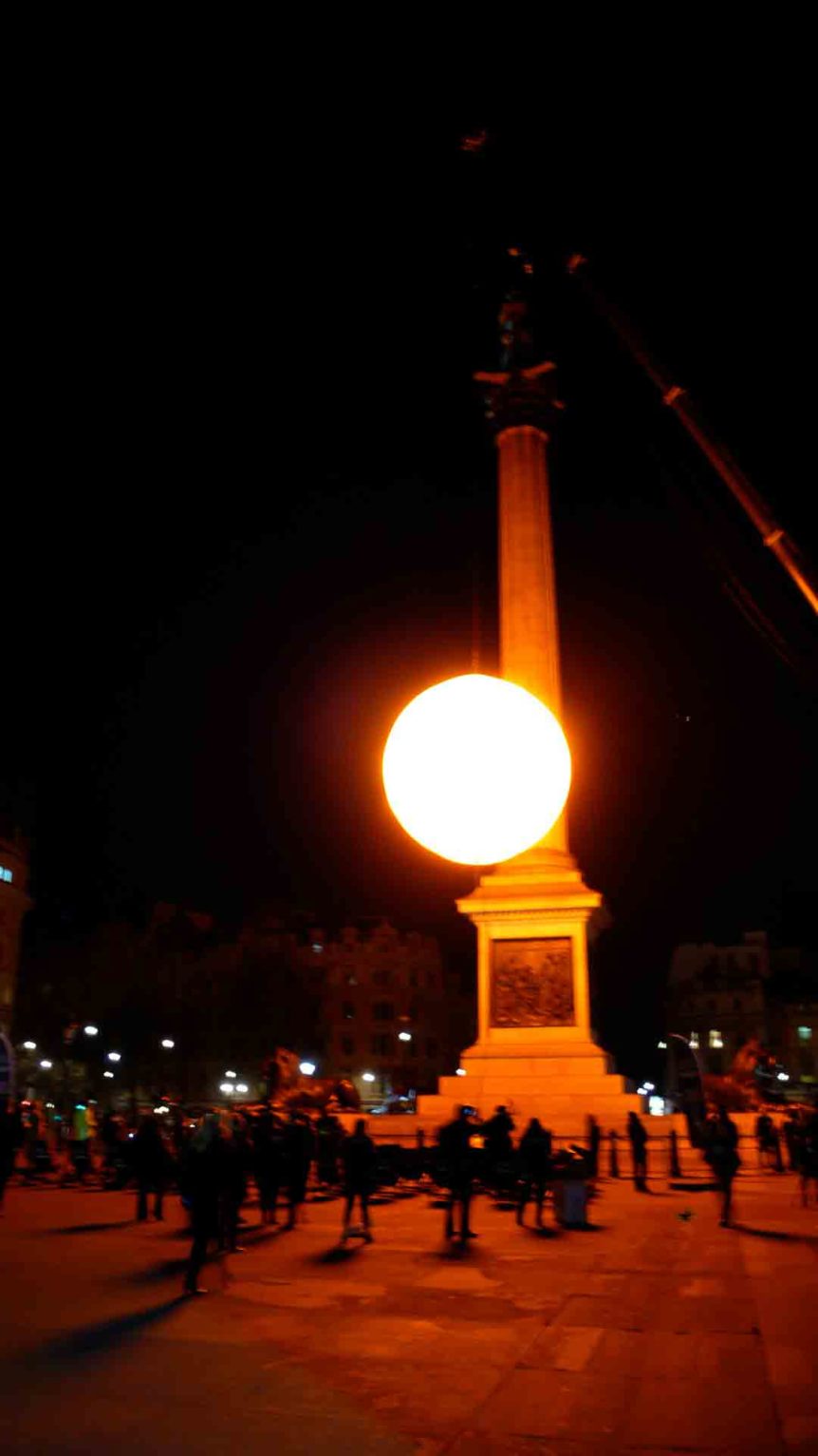 People watching inflatable sun in the dark at Trafalgar Square