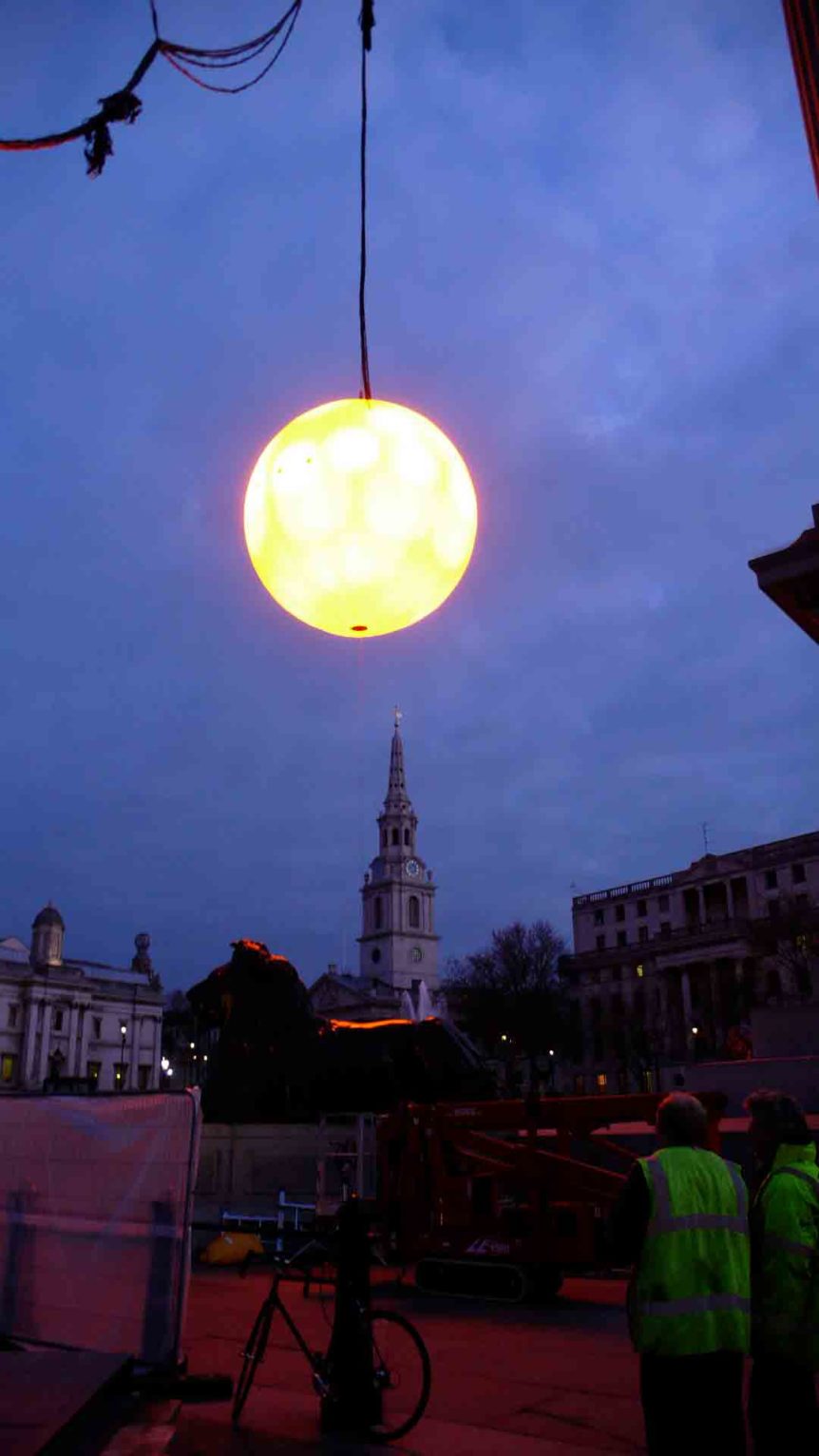 Inflatable moon light suspended with city skyline behind